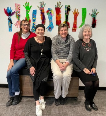 Four women sitting together and smiling at camera